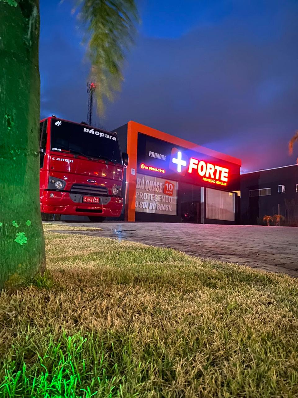 Fachada iluminada da Primore + Forte ao anoitecer, em Marau/RS, com um caminhão na frente